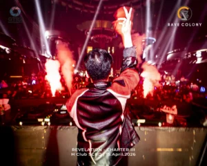 DJ facing away from the camera with raised arms in a neon lit nightclub flames and spotlights around event banner reads REVELATION   CHAPTER III on screen