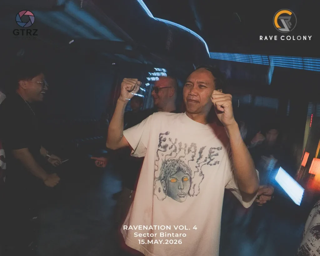A man in a light-colored t-shirt dancing with fists raised at a nightclub, event branding visible in the background: Ravenation Vol. 4, May 15, 2026.