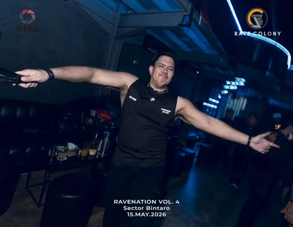 Man in a black sleeveless shirt stretches arms wide in a dim club with blue neon lighting; bottom text shows Ravenation Vol. 4, Sector Bintaro, 15 May 2026.