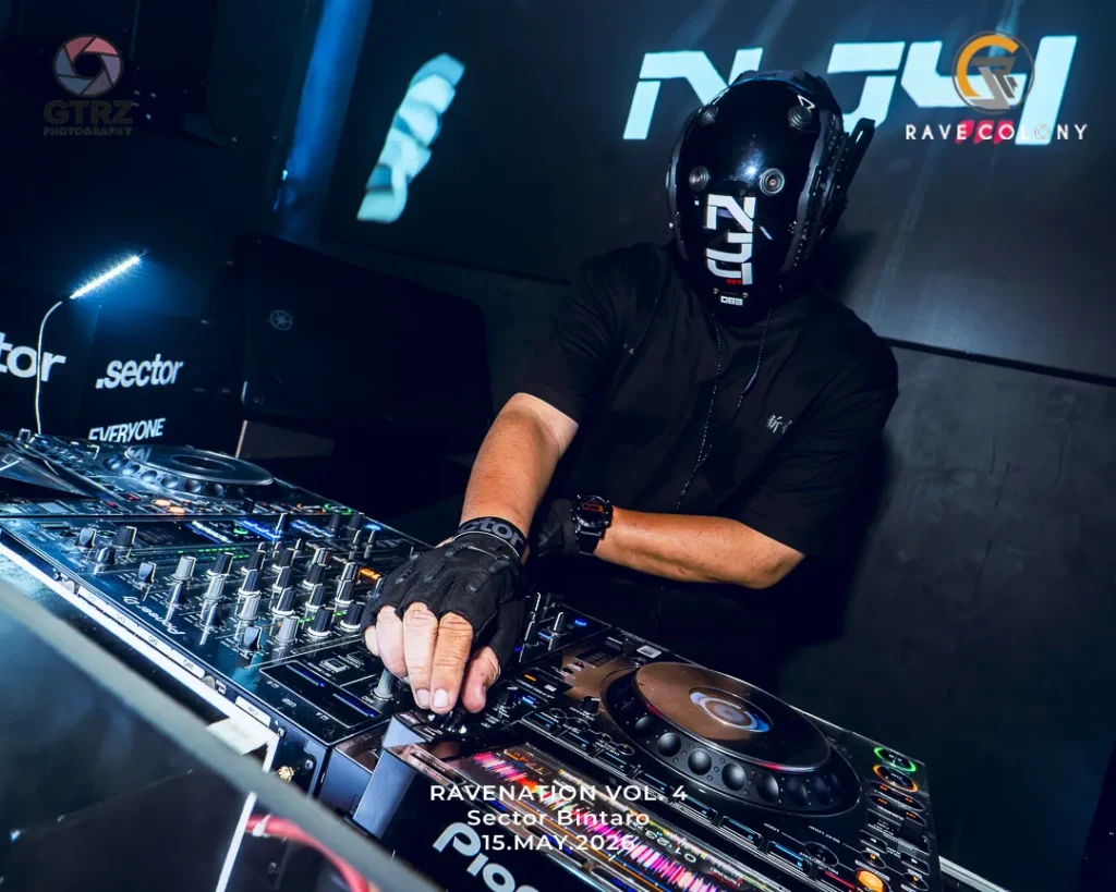 DJ wearing a sleek helmet performs at a club, hands on a Pioneer mixer with blue lighting and event text on screen