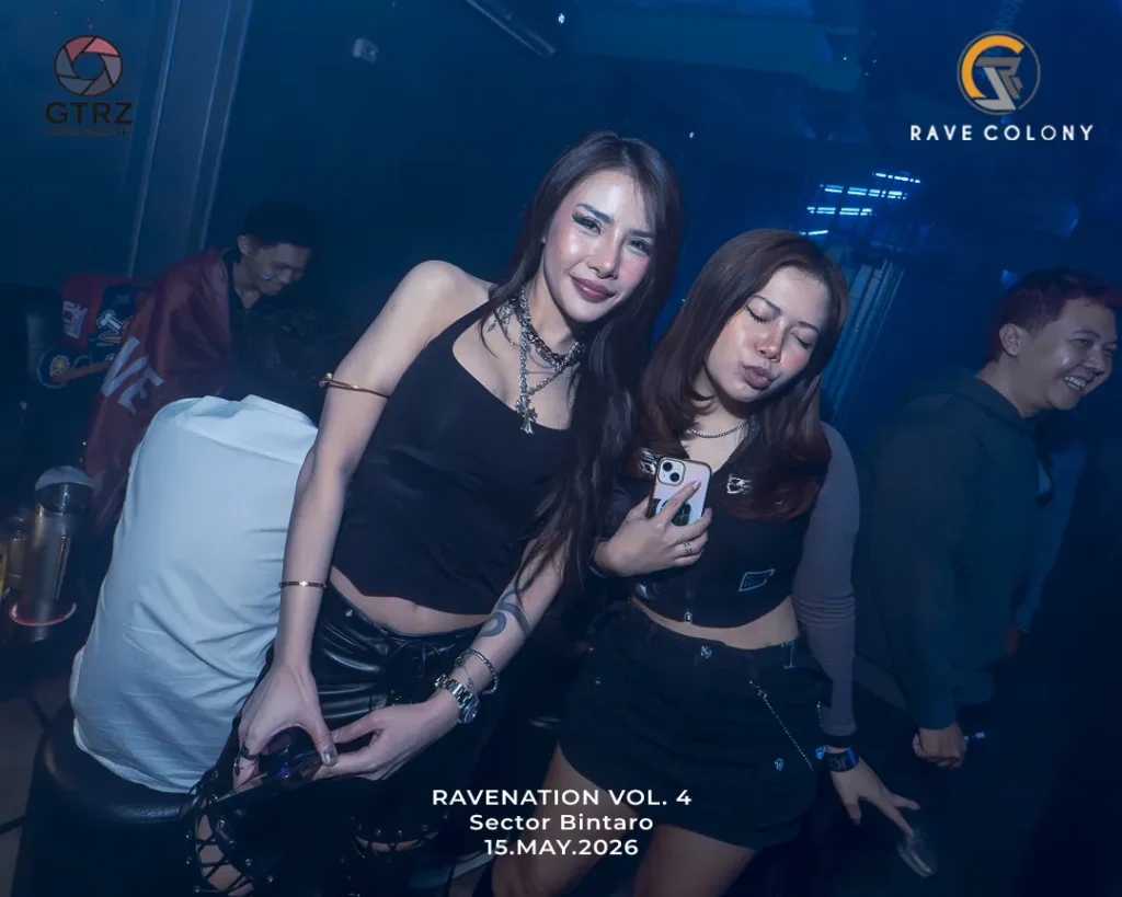 Two young women in black outfits posing and smiling in a nightclub with blue lighting; event text reads 'RAVENATION VOL. 4 Sector Bintaro 15.MAY.2026' at bottom