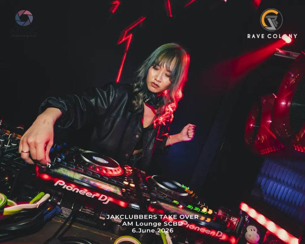 Female DJ in a black jacket operates Pioneer DJ gear on a club mixer, red lighting and event banner visible with 'JAK CLUBBERS TAKE OVER AM Lounge SCBD 6.June.2026'.