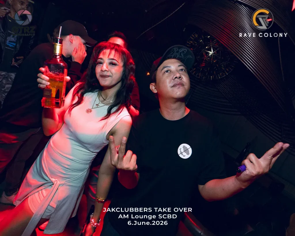 Woman in a white dress holds a bottle of liquor and poses with a friend at a dim club as event text appears: 'JACKCLUBBERS TAKE OVER AM Lounge SCBD 6.June.2026'.