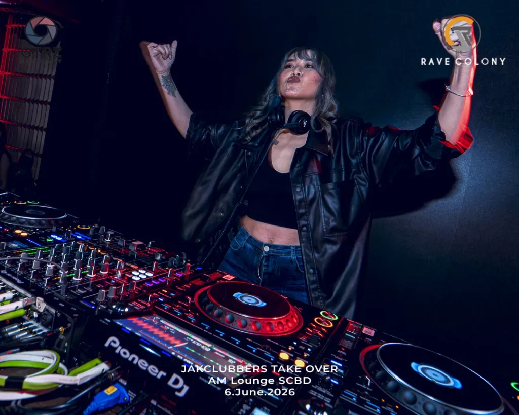 Female DJ in a black crop top and leather jacket behind a Pioneer DJ setup in a dark club, arms raised; event text at bottom reads 'JAK CLUBBERS TAKE OVER AM Lounge SCBD 6.June.2026'.