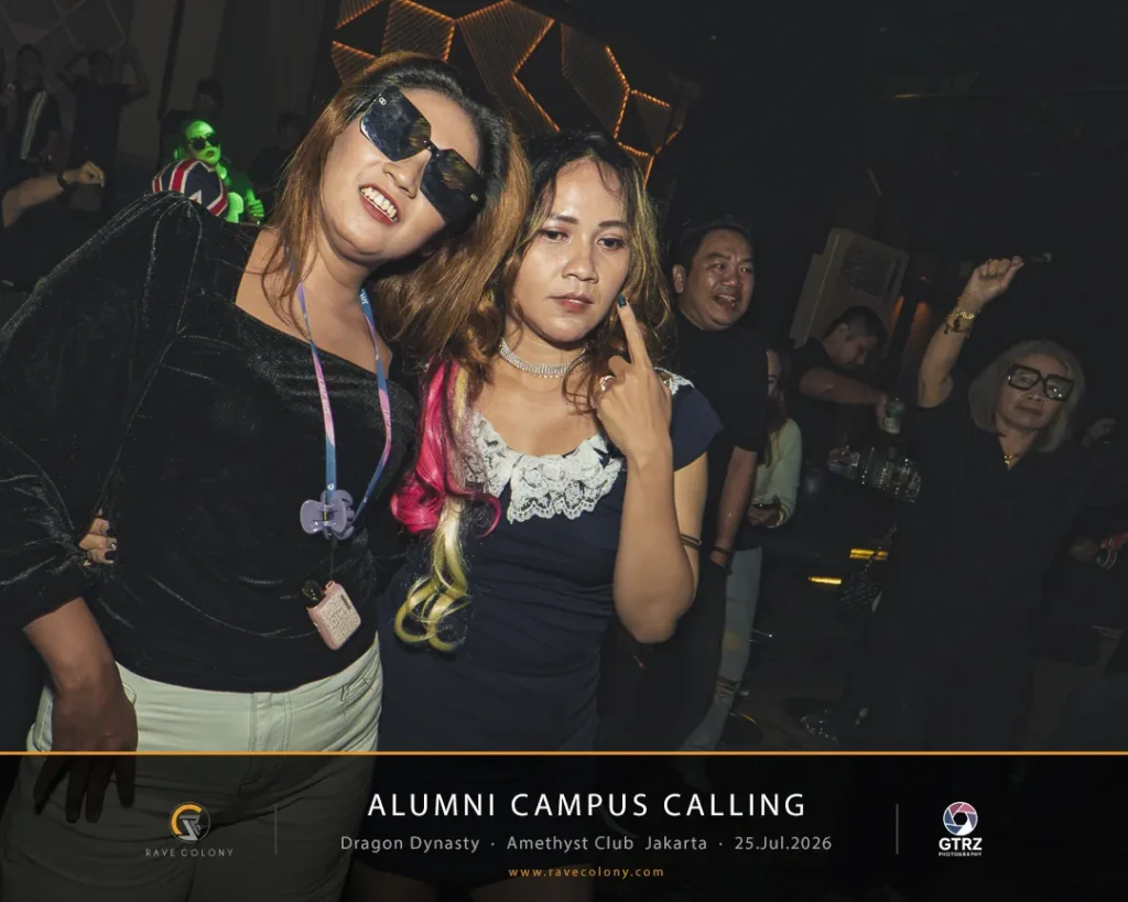 Two women pose for a photo at a nightclub during Alumni Campus Calling, with friends in the background and party lights.