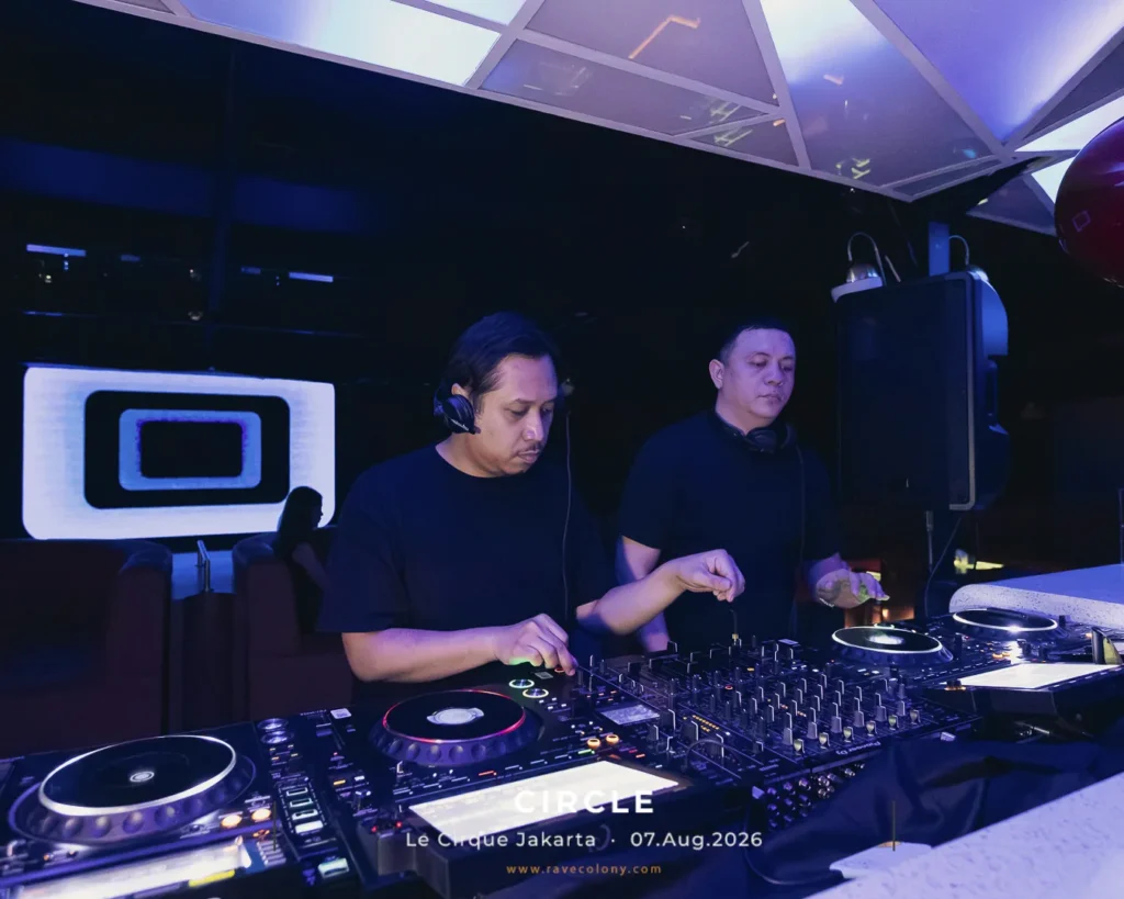 Two DJs in black shirts perform at a nightclub booth with mixers and turntables, blue lighting and a large speaker in the background, along with event text reading 'CIRCLE Le Cirque Jakarta 07.Aug.2026' at the bottom.